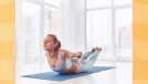 focused woman doing locust pose on yoga mat in bright room surrounded by windows