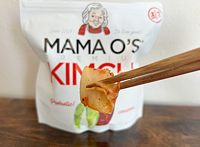 a bag of mama o kimchi with chopsticks holding kimchi 