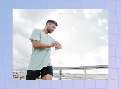 man checking heart rate monitor while running outdoors on sunny day