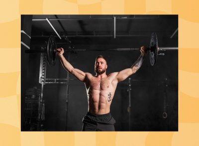 muscular man doing a barbell overhead press in a dark gym