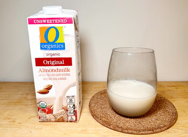 O organics almond milk container next to a glass of it 