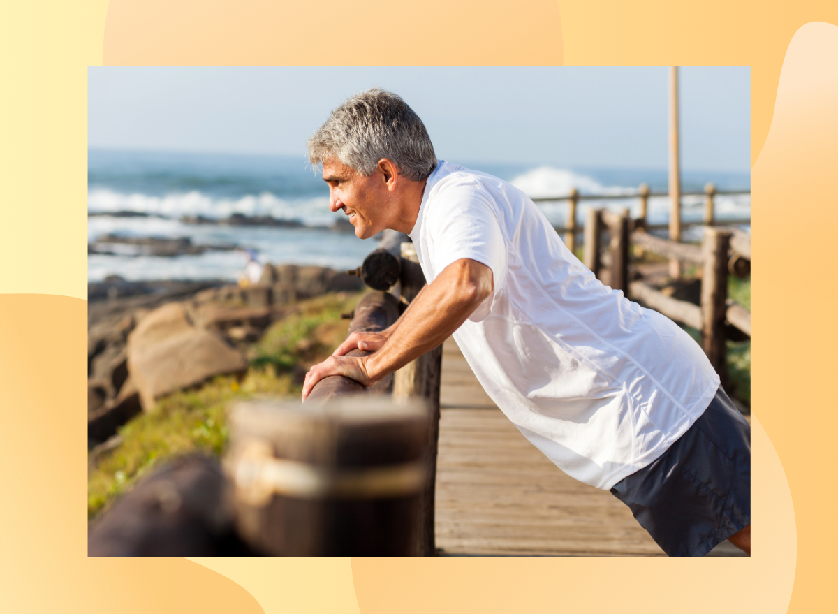 fit senior man doing incline pushups on a beach walk railing