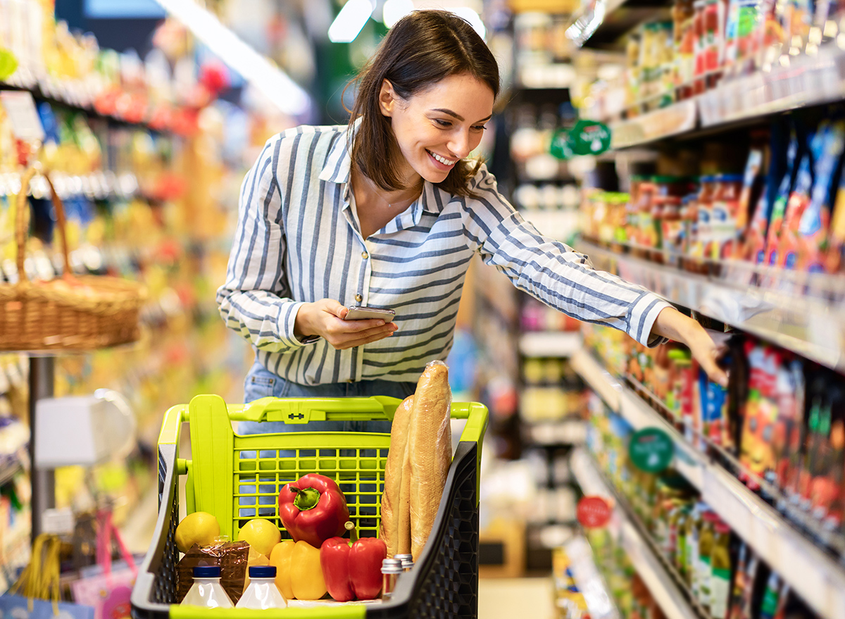 Grocery,Shopping.,Young,Smiling,Woman,Holding,And,Using,Mobile,Phone,Buying