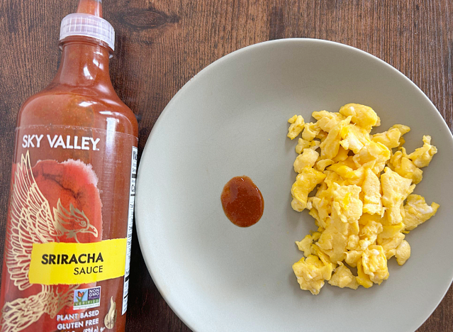 sky valley sriracha bottle next to a plate of eggs with a dollop of sriracha 
