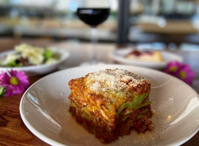 a plate of lasagna from storico fresco with wine and floral garnish 