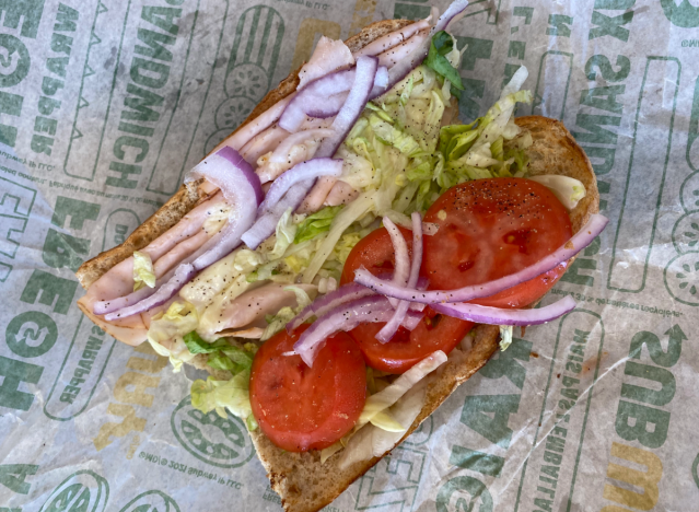 a turkey sub openfaced on a paper from subway 