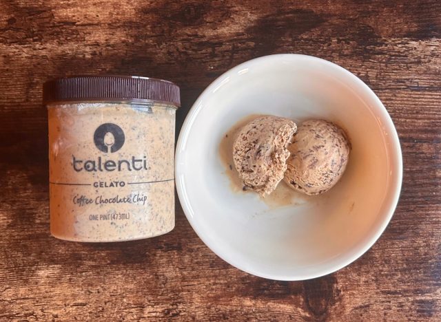 a container of talenti chocolate chip gelato next to a bowl of the gelato on a wooden table background