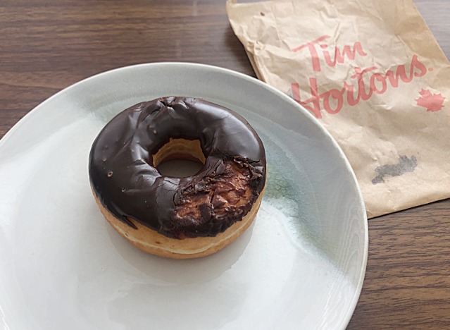 tim horton's chocolate frosted donut on a plate next to a bag 