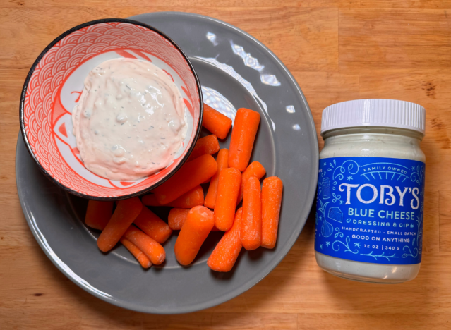 a jar of toby's blue cheese next to a plate of carrots 