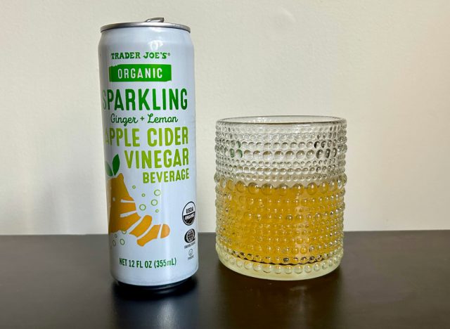 can of trader joe's organic sparkling ginger + lemon apple cider vinegar beverage next to a glass of the drink