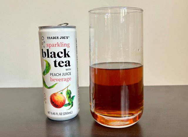 can of trader joe's sparkling black tea with peach juice next to a glass of the beverage