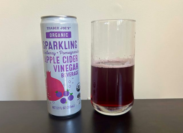 can of trader joe's organic sparkling elderberry + pomegranate apple cider vinegar beverage next to a glass of the drink
