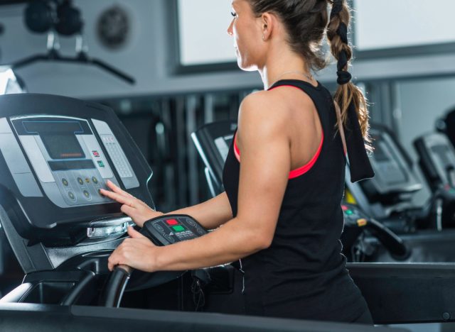 woman adjusting the treadmill incline at the gym