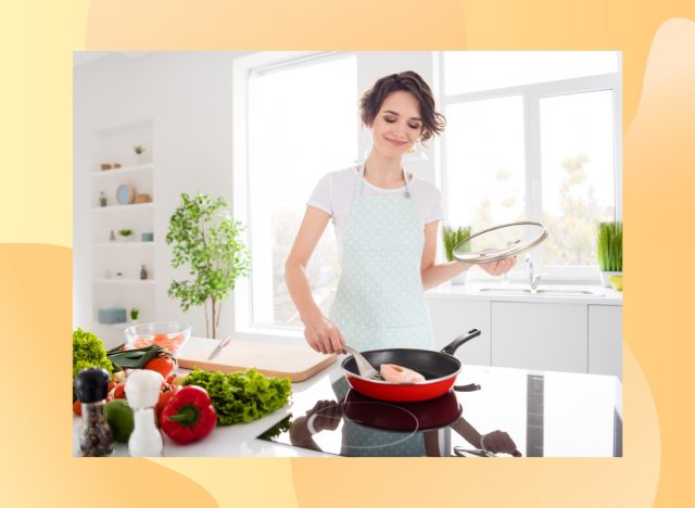 happy woman cooking salmon in bright kitchen