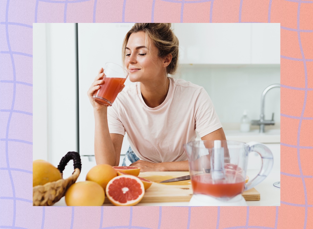 woman drinking fresh grapefruit juice in bright kitchen by counter with sliced grapefruit