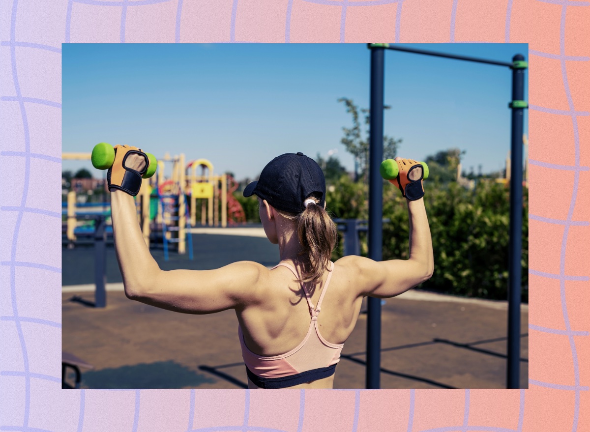 fit woman doing dumbbell shoulder presses outdoors near playground on sunny day