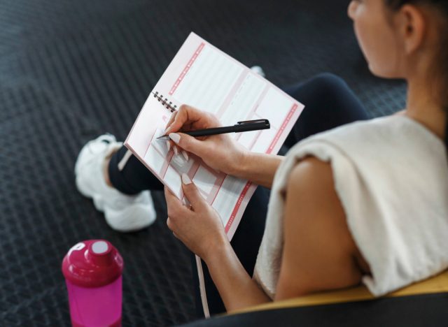 close-up of woman writing in fitness calendar at the gym