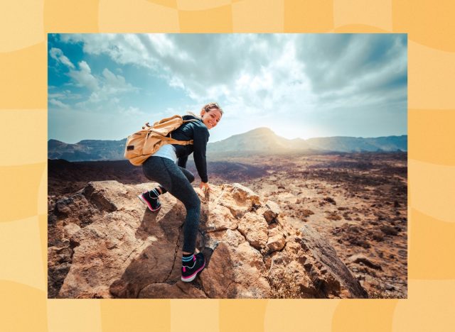 happy woman hiking outdoors through mountain terrain