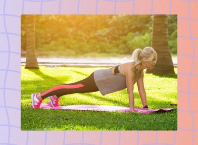 fit blonde woman holding the plank position on pink yoga mat in the park on a sunny day