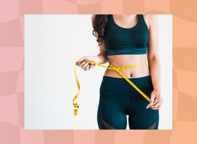 close-up of woman in workout clothes measuring her waistline with tape measure