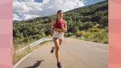 female runner running outdoors on road on sunny day by mountain