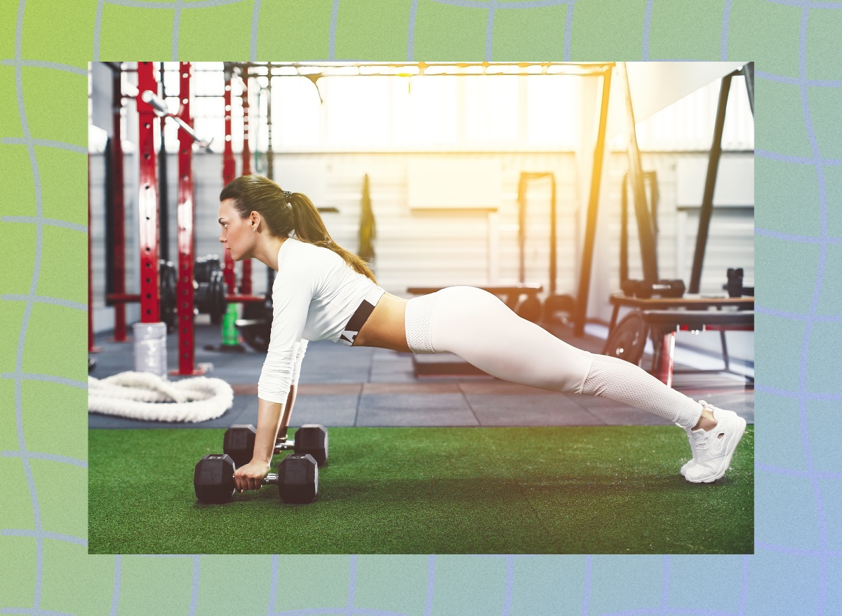 fit brunette woman doing plank rows at the gym on turf