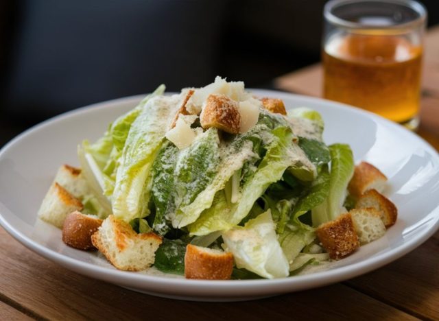 Caesar salad in bowl on wooden table