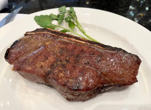 A bone-in dry aged New York strip served on a white plate at the Capital Grille in NYC