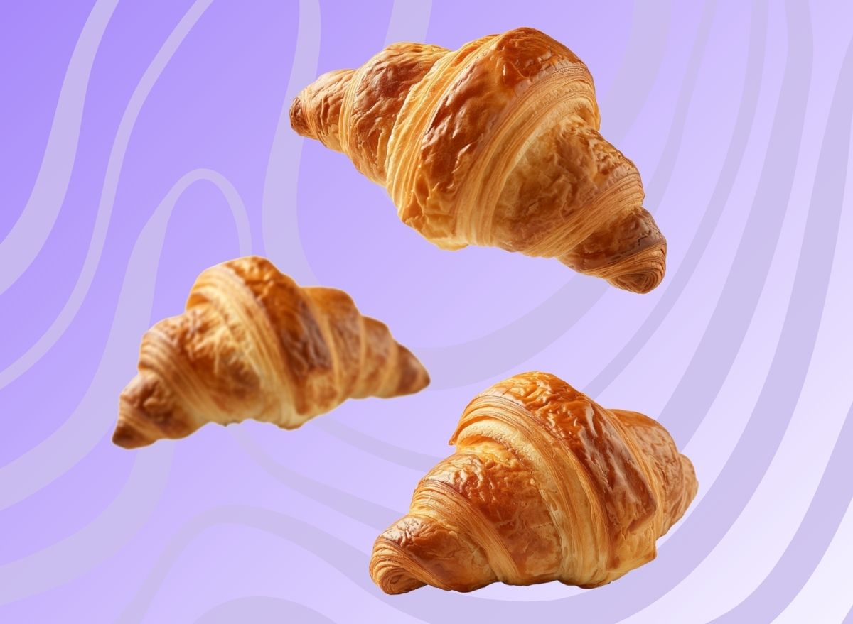 A trio of French-style croissants set against a vibrant purple background