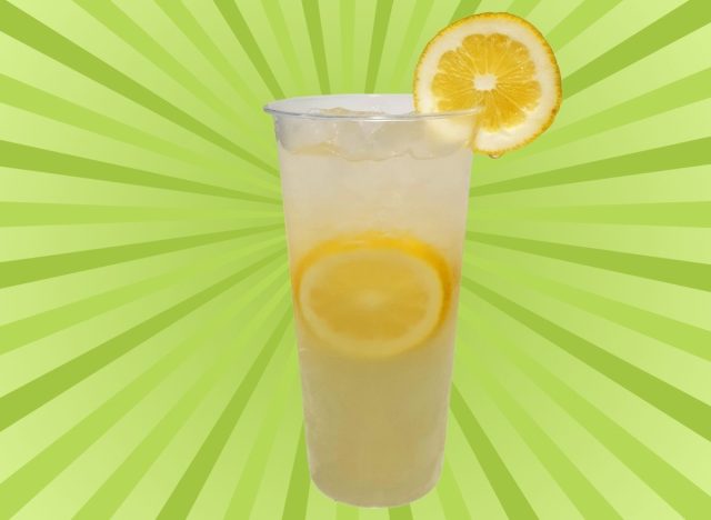 A tall plastic cup of lemonade set against a vibrant green background