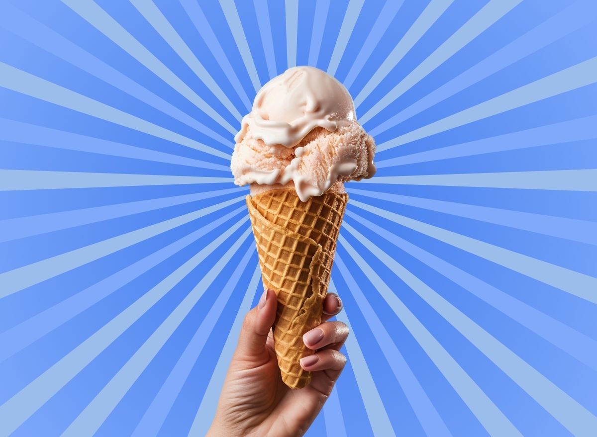 Hand holding ice cream cone in front of striped blue background