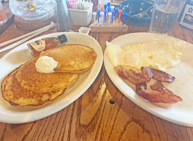 Three buttermilk pancakes topped with butter & served with two eggs, bacon or sausage and maple syrup at Cracker Barrel