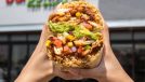 Burrito from Burritobar being held up in front of a storefront