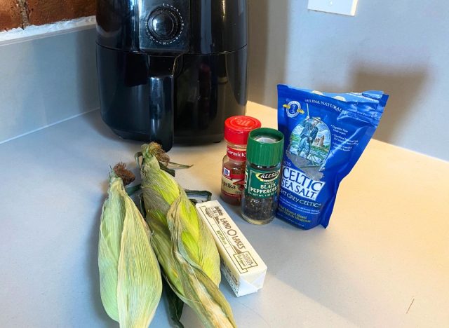 corn, butter, and seasonings on a countertop next to an air fryer