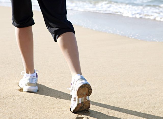 close-up of woman's sneakers, walking on the sand on the beach