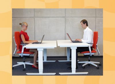 coworkers seated at a shared desk space typing on their laptops