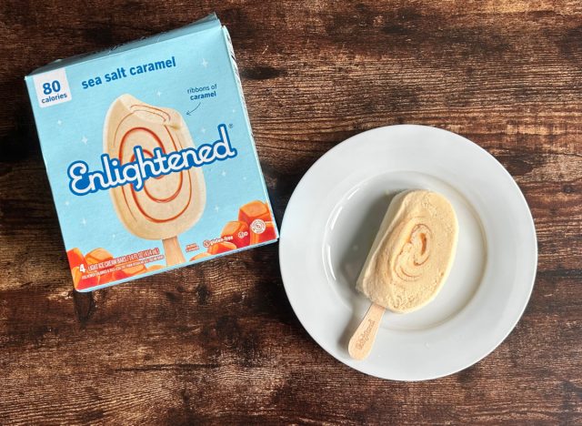 a box of enlightened sea salt caramel bars next to a plate with an enlightened bar