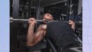 man doing bench press exercise at the gym in dark weight room