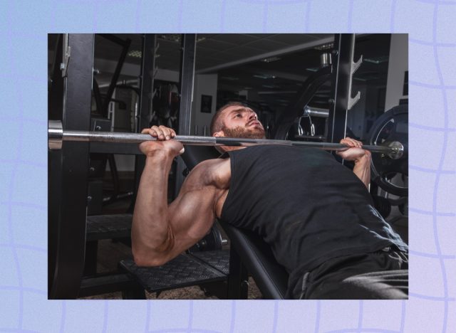 man doing bench press exercise at the gym in dark weight room