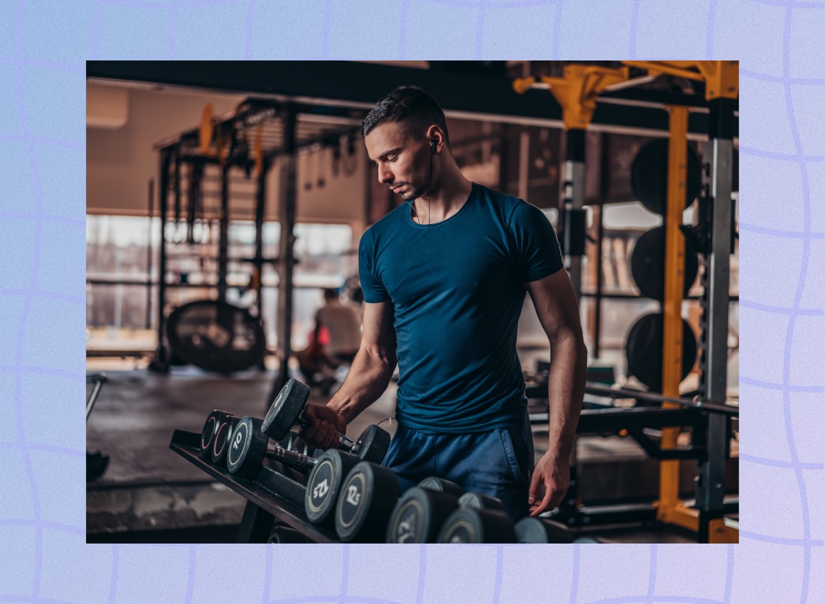 fit muscular man choosing dumbbells from a rack at the gym