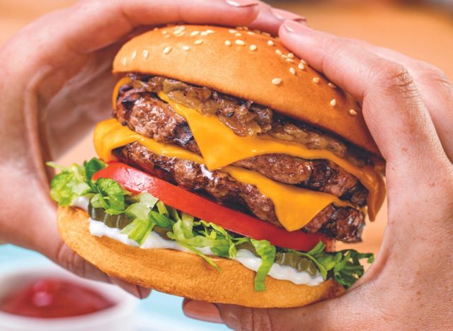 person holding habit burger grill's double char burger