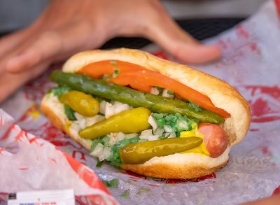 Loaded hot dog with pickles peppers, tomatoes on a bun from Portillo's