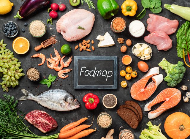 Fodmap diet concept. Low fodmap ingredients - poultry meat, fish, seafood, vegetables and fruits and words Fodmap in center, on dark background. Top view or flat lay.
