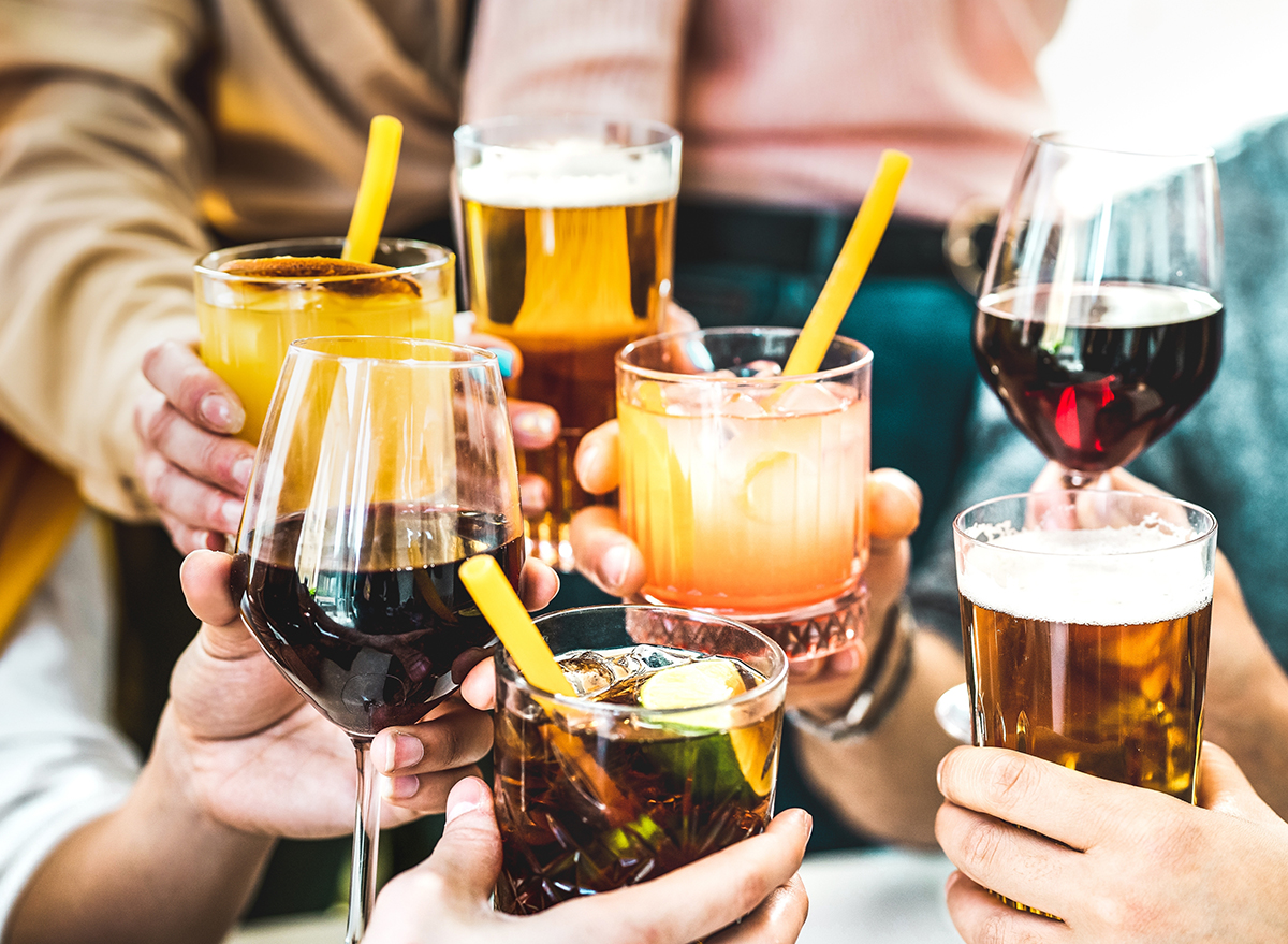 Friends hands toasting fancy cocktails - Young people having fun together drinking beer and wine at happy hour - Social life style party time concept on vivid filter - Focus on lower cuba libre drink