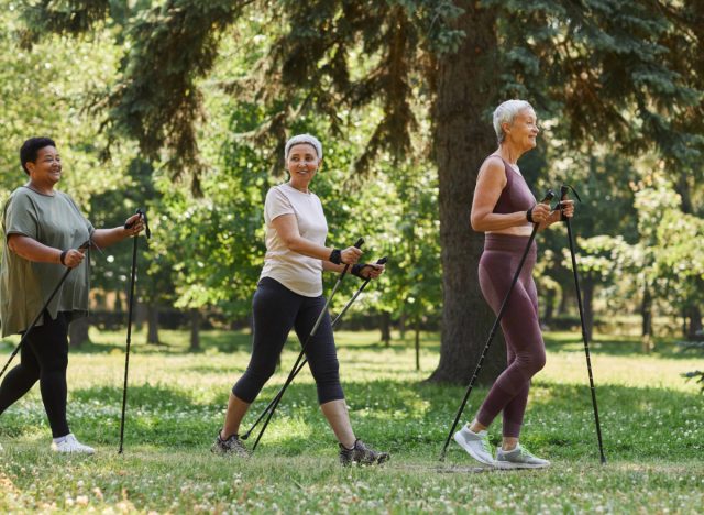 mature women with walking poles walking through nature for exercise