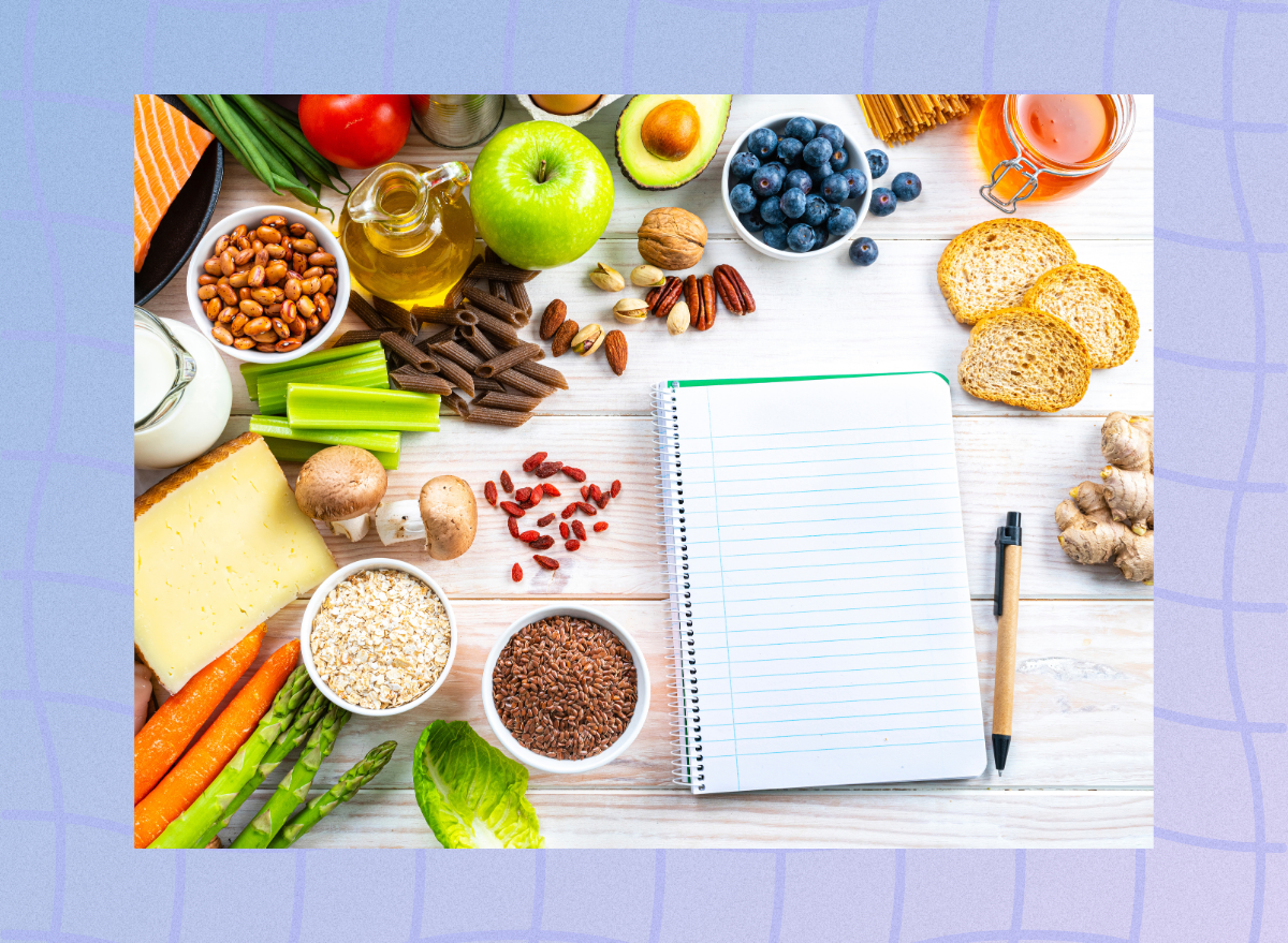 flat lay of healthy foods around a blank notepad and pen shopping list concept