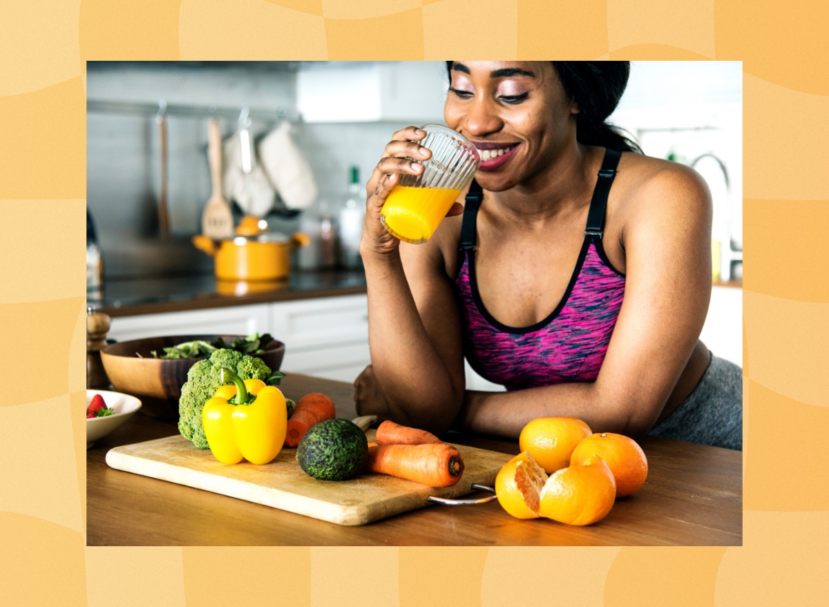 happy woman drinking homemade orange juice in her kitchen