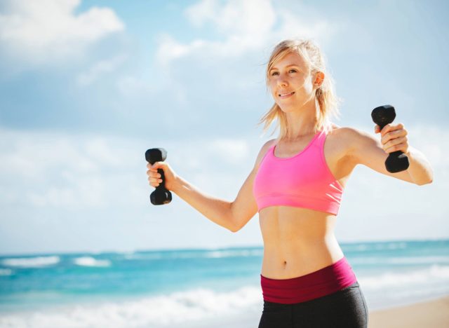 woman doing a dumbbell workout at the beach