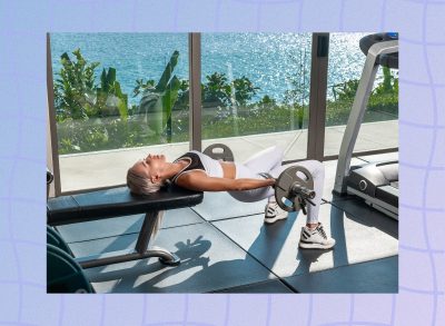 woman doing hip thrust exercise with barbell at gorgeous gym with view of the ocean