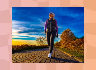 fit woman walking outdoors at sunset along path by the beach